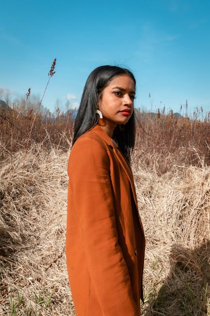 Chic portrait of a young woman in a bohemian style jacket with natural backdrop.