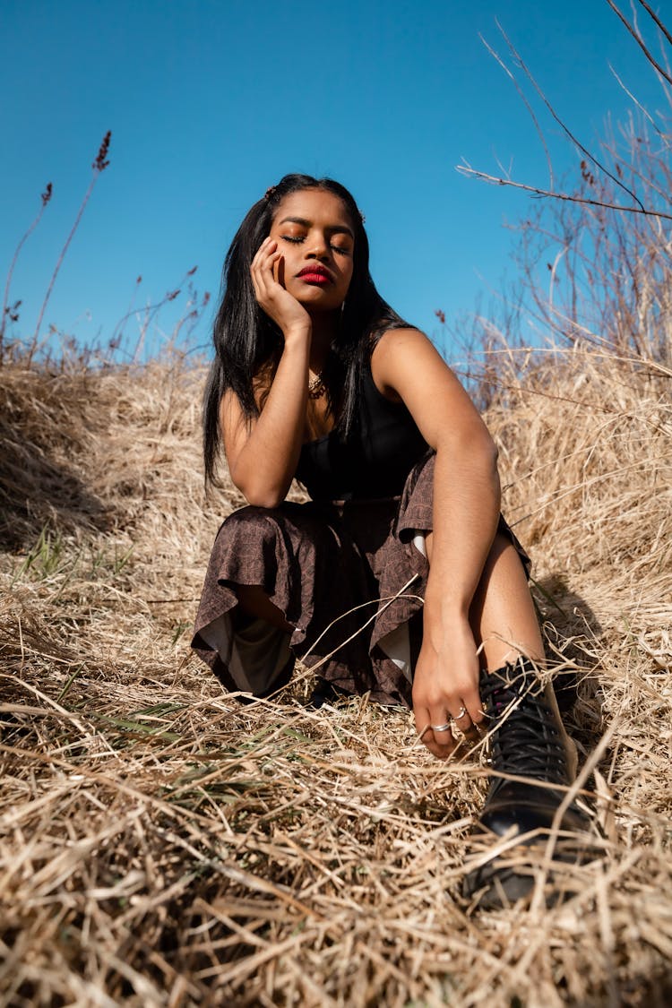 Brunette Woman Sitting With Eyes Closed On Grassland