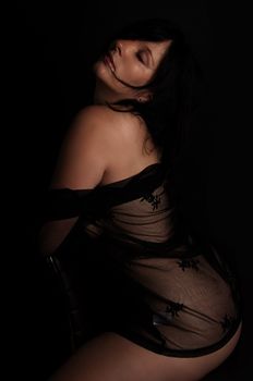 Elegant portrait capturing a woman in black lace, exuding sensuality and allure against a dark background.