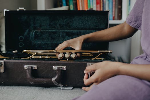 Close-up of hands with a brass trumpet on a case, indoors setting.