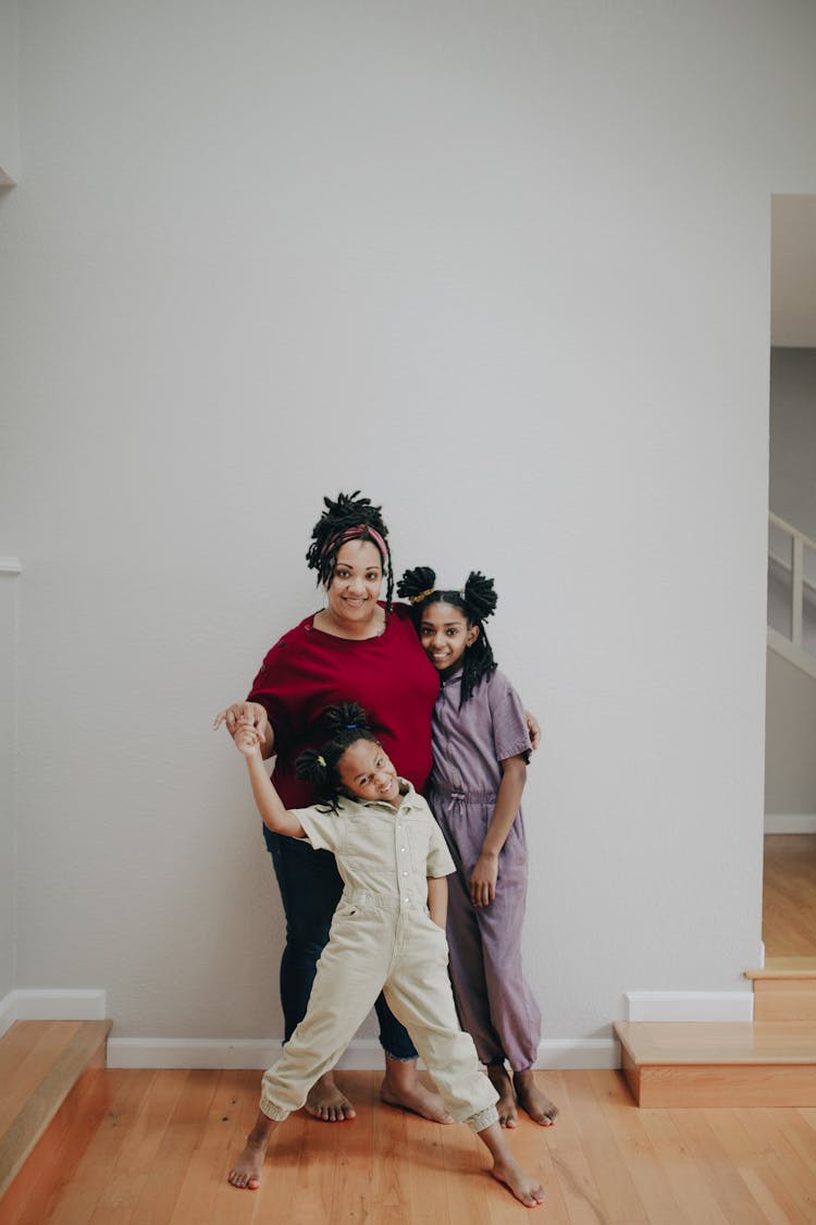 A Woman Posing Indoors With Her Daughters