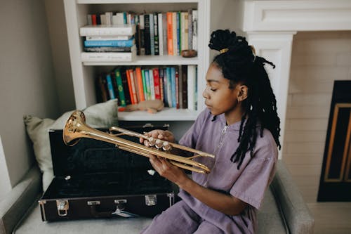 Young Girl Sitting on a Sofa and Holding a Trumpet