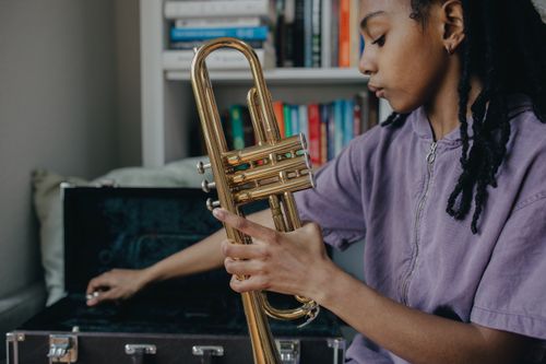 Free Child musician holding a brass trumpet indoors with focus on music and learning. Stock Photo