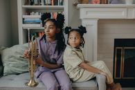 A Woman Beside a Girl on the Couch Holding a Trumpet
