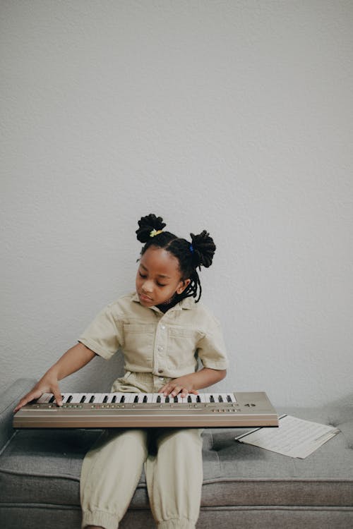 Free Girl in Beige Polo Playing an Electronic Keyboard Stock Photo