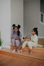 A Happy Child Holding a Trumpet while Sitting with her Sister on the Floor