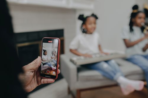 Free Siblings play music together at home while being recorded on a smartphone. Stock Photo