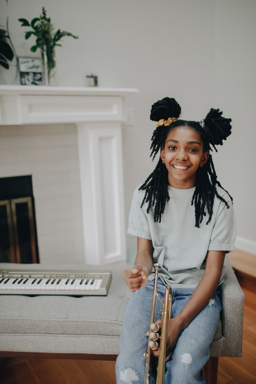Free Smiling young woman with a wind instrument indoors, enjoying music. Stock Photo