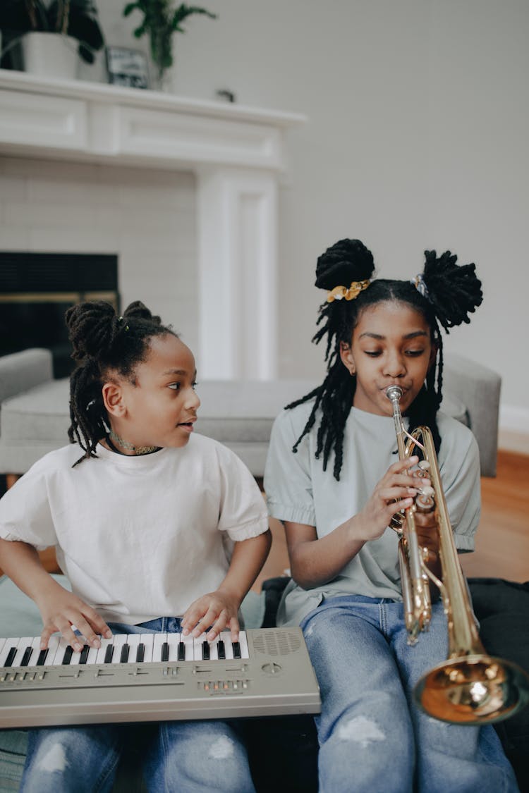 Young Girls Sitting While Playing Musical Instruments