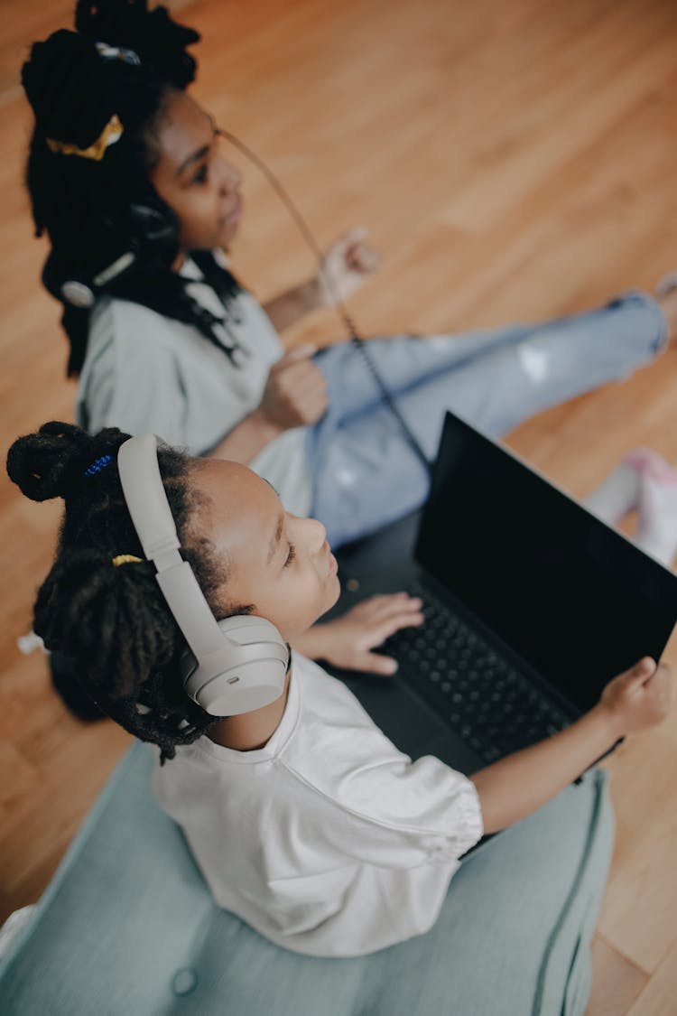 Kids Listening To Music Using Headphones While Sitting On A Wooden Flooring