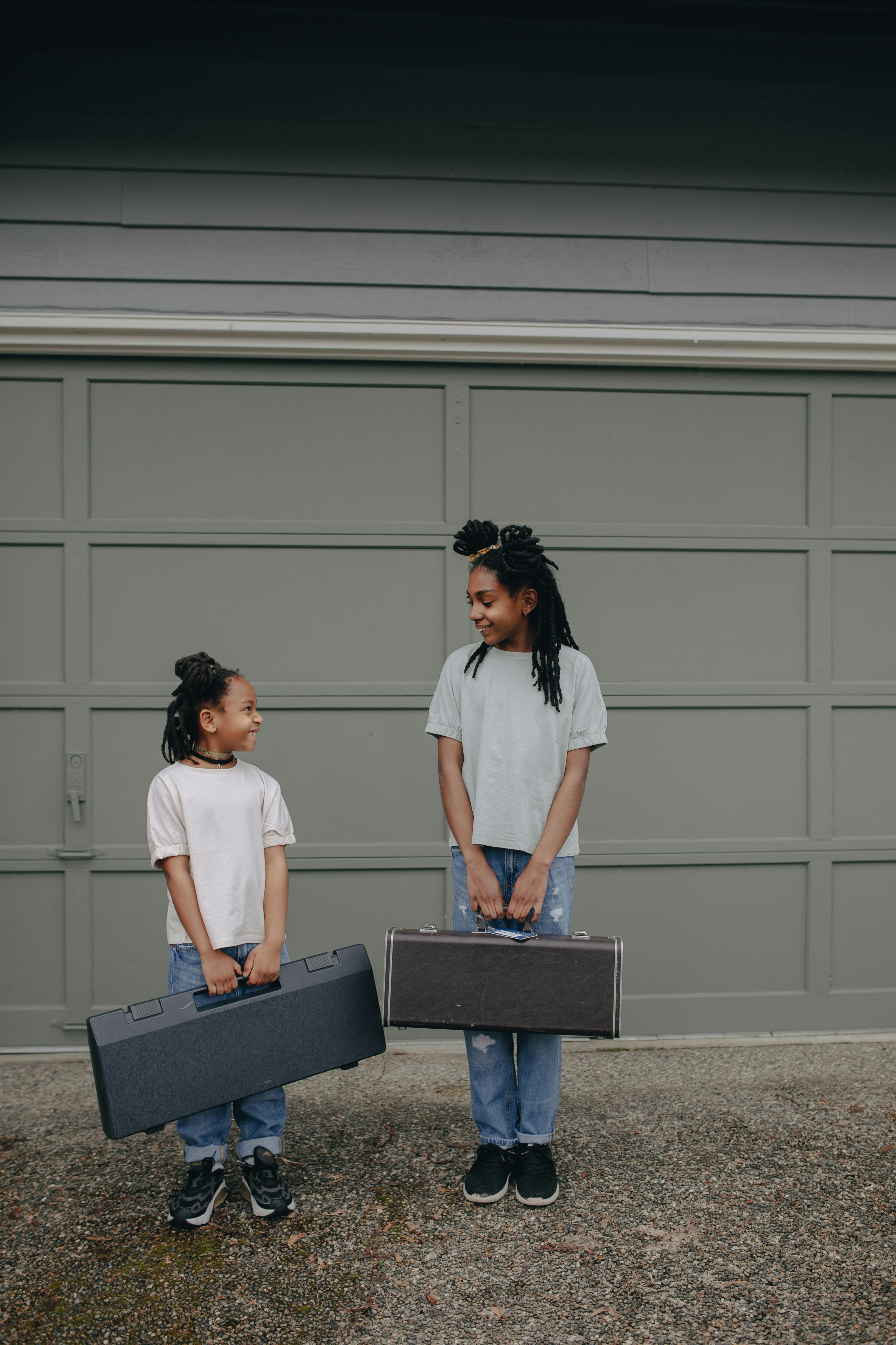 two girls with hand carry cases standing next to each other