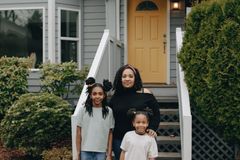 A joyful family standing together in front of their house with a yellow door, exuding warmth and happiness.