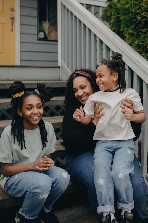 Free A Happy Family Sitting on a Wooden Stairs on the Entrance of their House Stock Photo