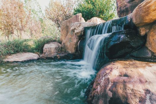 Peaceful waterfall cascading over rocks surrounded by lush foliage.
