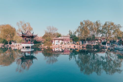 Free Picturesque view of a traditional Chinese garden with blue sky and lake reflections. Stock Photo