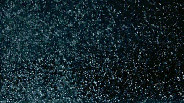 Close-up of water bubbles creates an abstract pattern against a dark background.