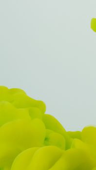 Abstract photography of vibrant yellow ink swirling against a white background, perfect for creative projects.