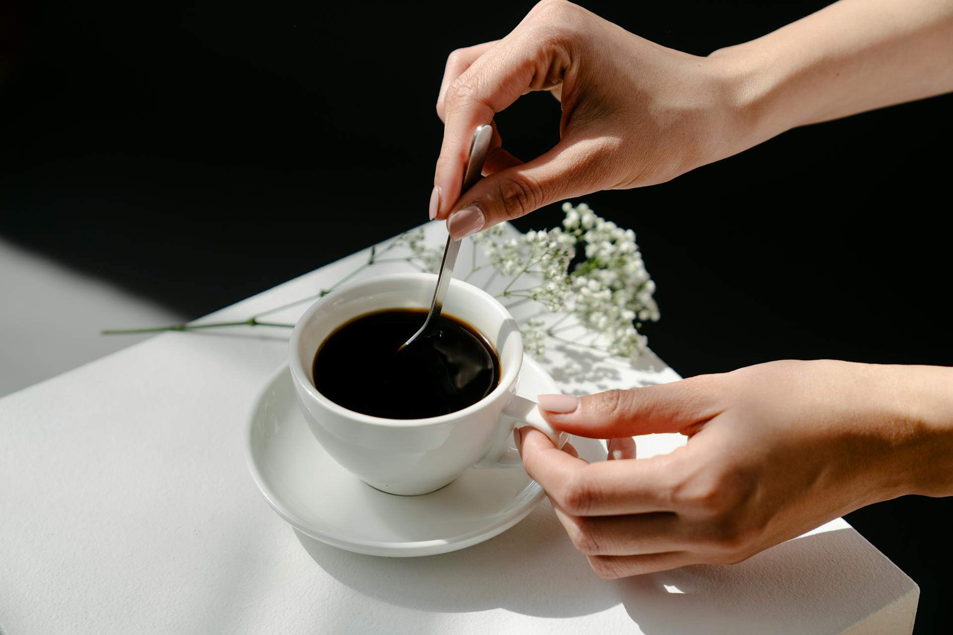 Anonymous woman stirring coffee near twigs