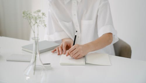 Free Crop person writing in notebook at table Stock Photo