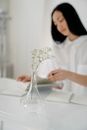 Twig in vase on background of ethnic female making notes