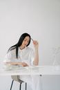 Asian woman scratching head with pencil while reading notepad