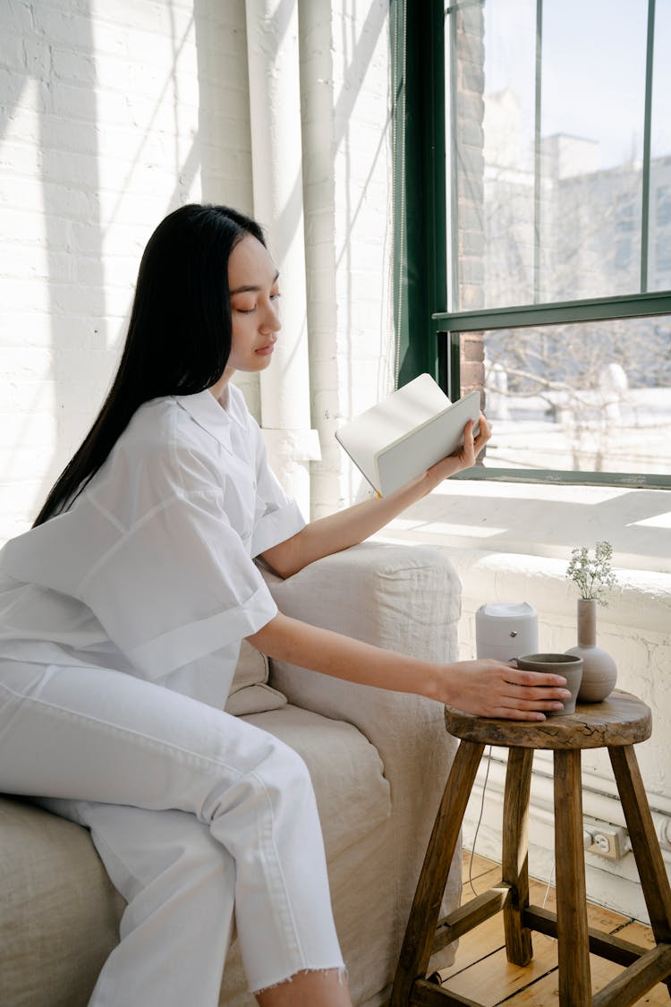 Young Asian Woman With Opened Notebook Taking Teacup