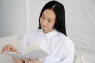 Young Asian woman flipping page of book