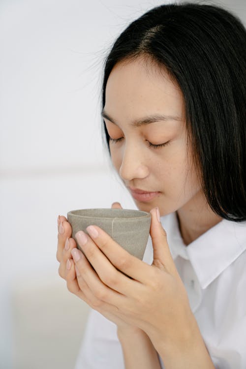 Free Asian woman smelling hot tea in cup Stock Photo