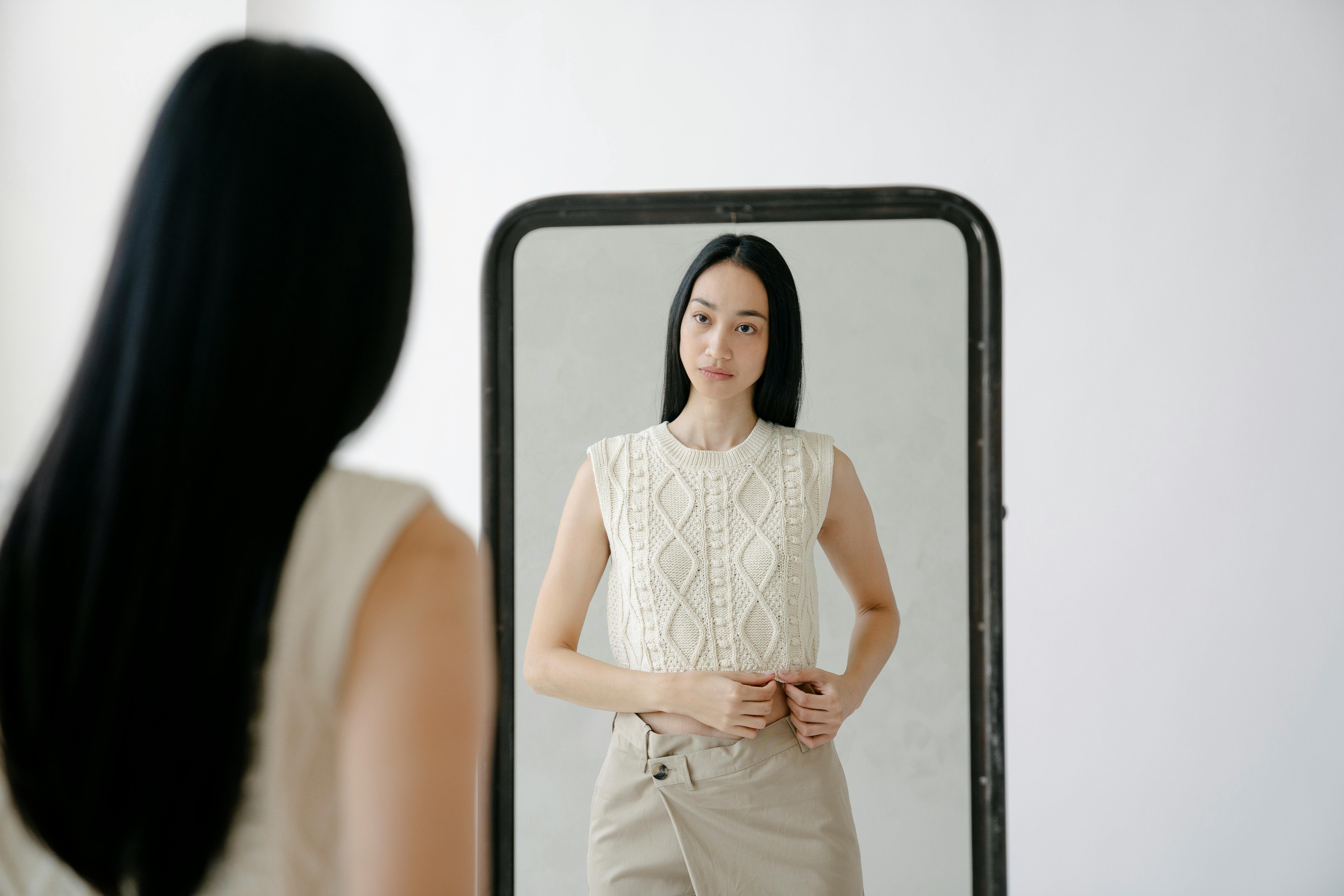 young ethnic woman looking at mirror