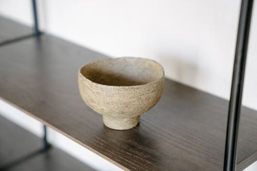Close-up of an Uneven Clay Bowl Standing on a Shelf 