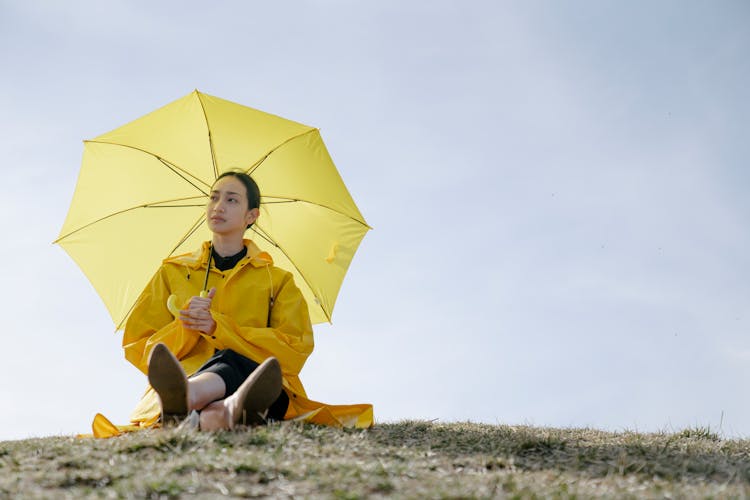 Woman In A Raincoat Holding A Yellow Umbrella