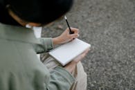Person Writing on Notebook