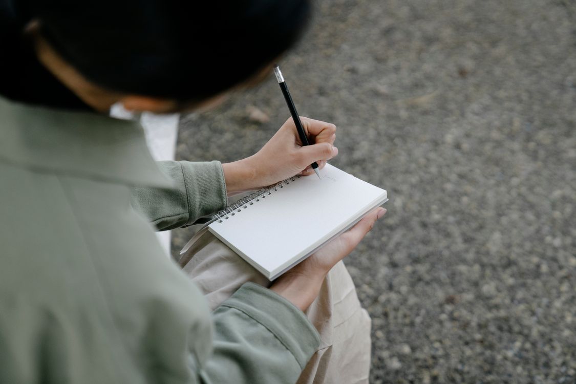 Person Writing on Notebook · Free Stock Photo