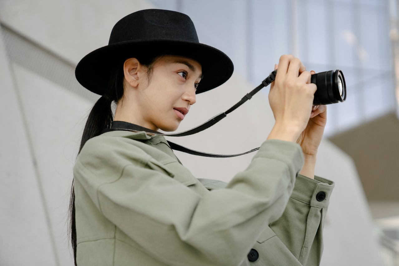 Woman in a black felt fedora holding a camera