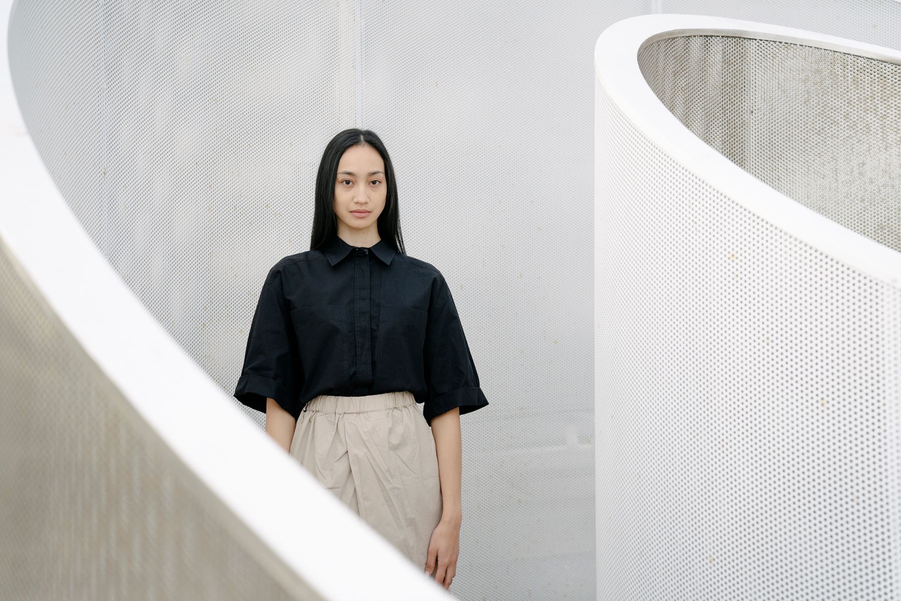 Woman wearing a black shirt and beige trousers in a calm architectural interior