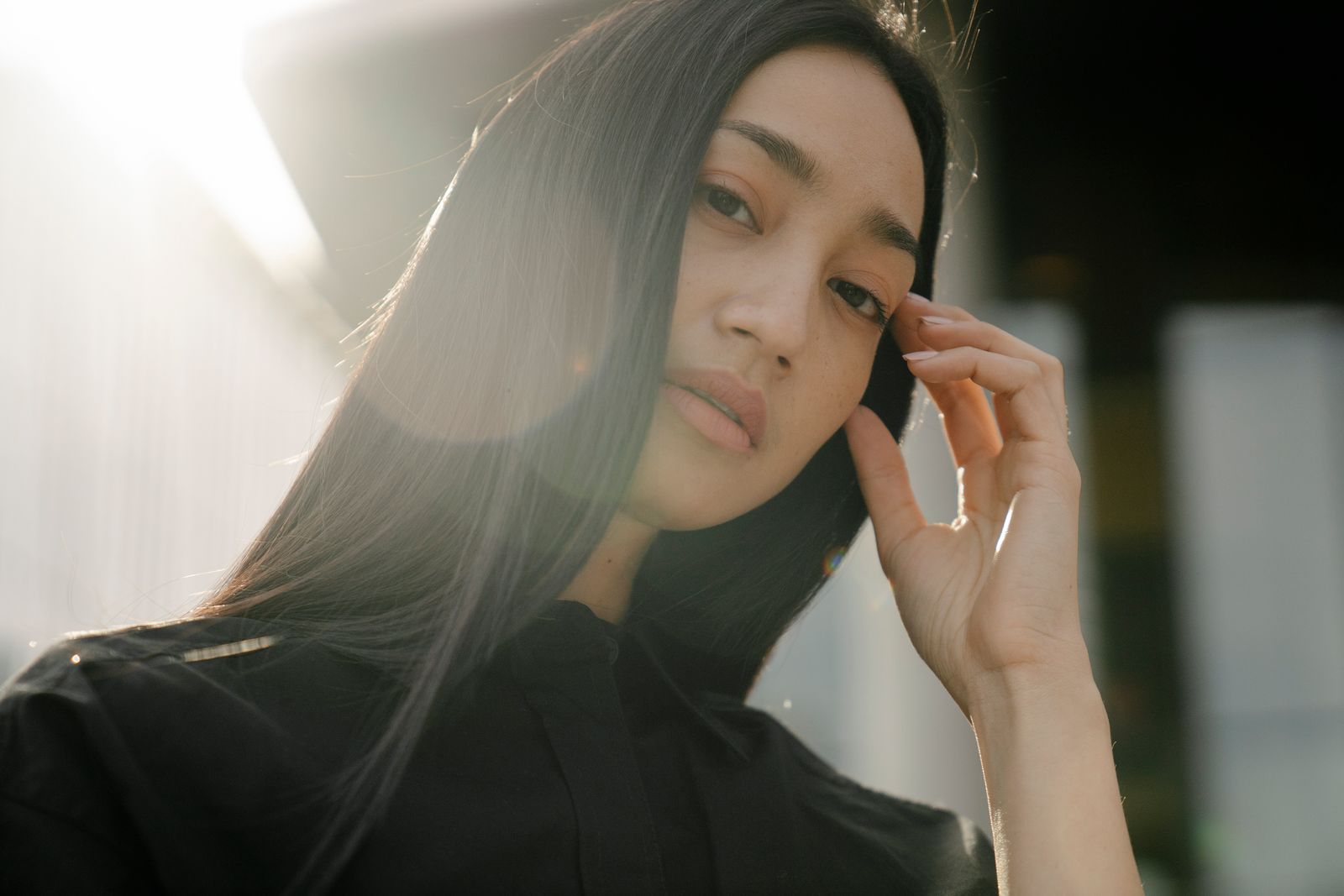 Brunette woman touching her sleek hair in warm sunlight outdoors