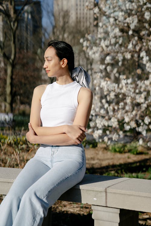 Free Gentle Asian woman resting on bench in city park Stock Photo
