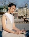 Asian woman writing in diary on urban bench