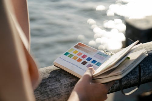 Free Crop artist with painted spectrum in notebook Stock Photo