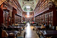 在优雅的图书馆里，人们正在学习，周围环绕着木制书架和古典建筑