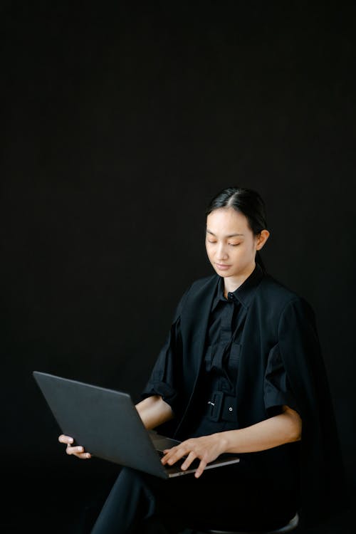 Busy ethnic female entrepreneur typing laptop while sitting on chair