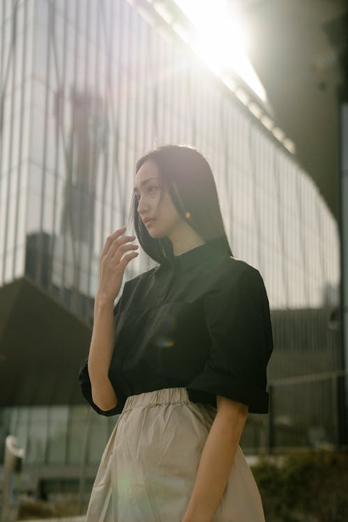 Serious Asian woman standing near modern multistory building