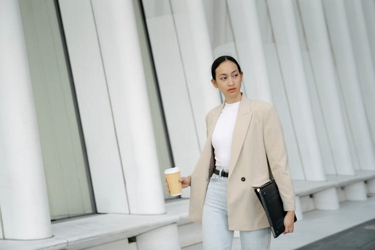 Serious Ethnic Woman With Takeaway Coffee And Folder