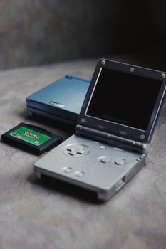 Classic portable game consoles and cartridge on table, nostalgic gaming gear.