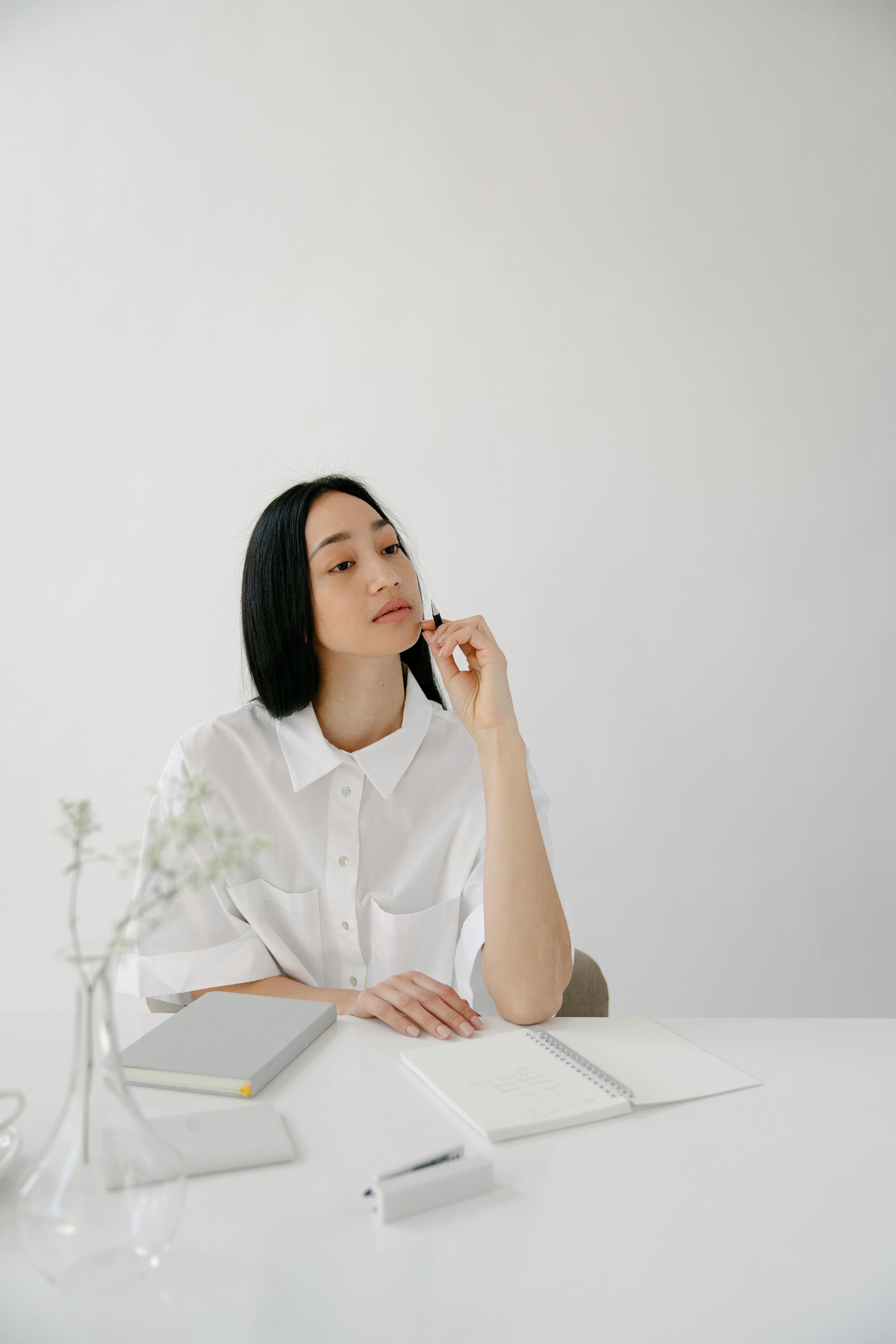 thoughtful asian employee with agendas at office table