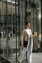 Stylish ethnic entrepreneur with laptop and takeaway coffee in town