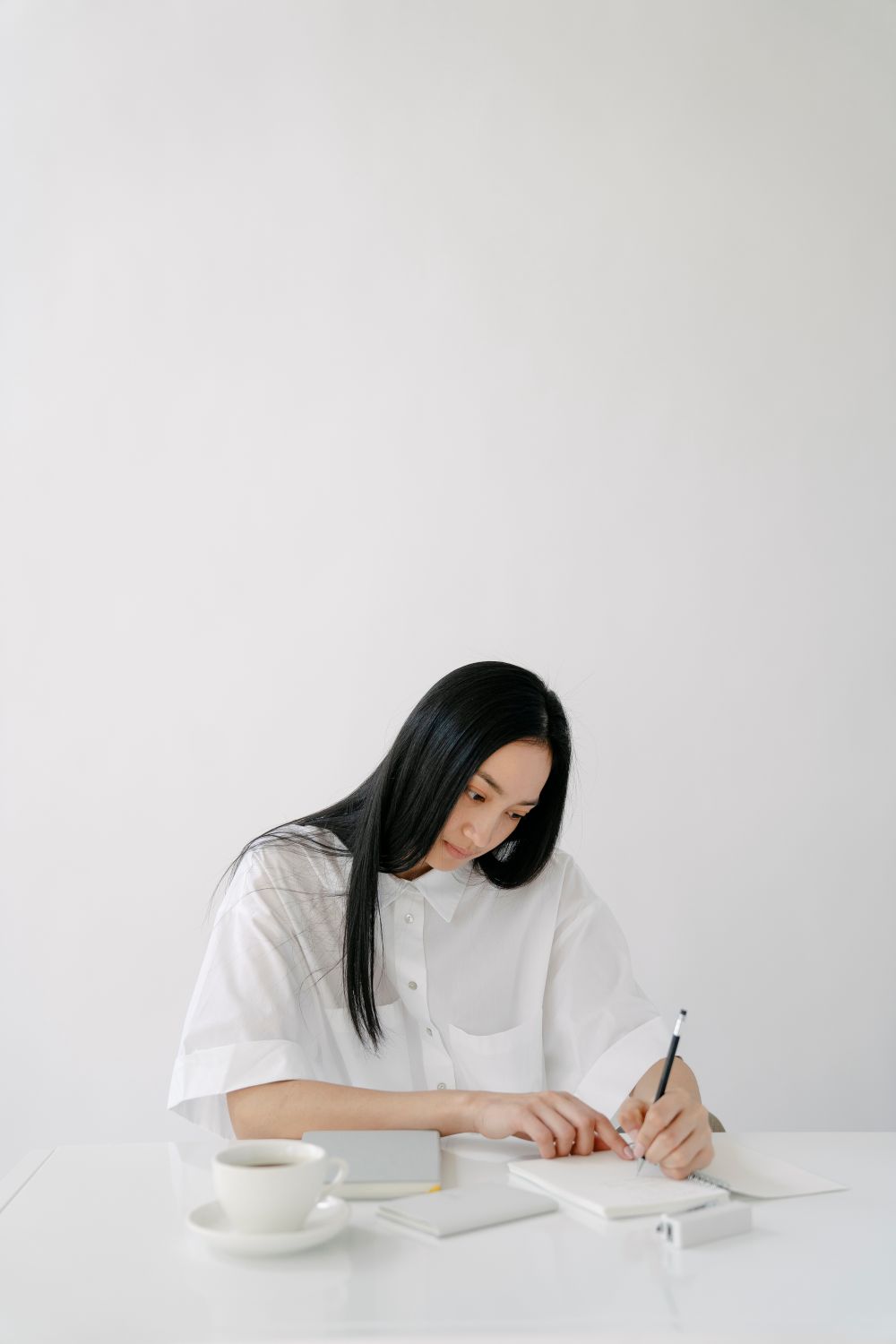 The copywriter writing in a notebook at a white desk