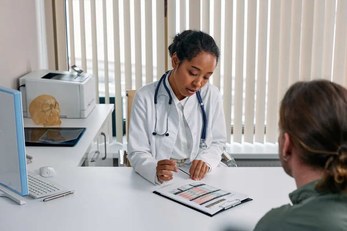 Female doctor reviewing a patient’s chart during a medical consultation, emphasizing the importance of healthcare and patient communication.