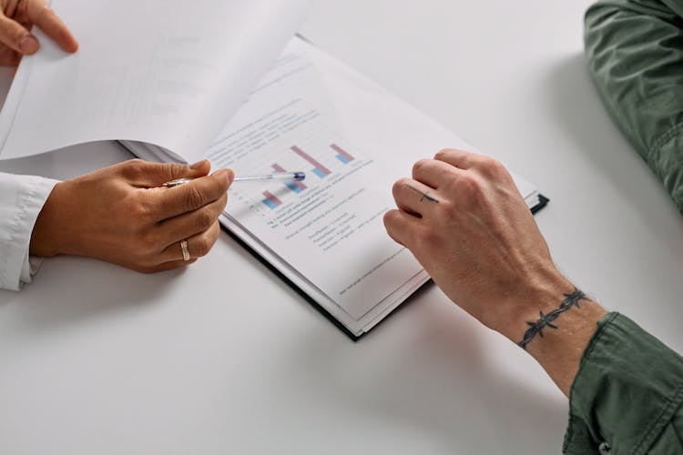 Hand Of A Person Holding A Pen On A Graph On Paper