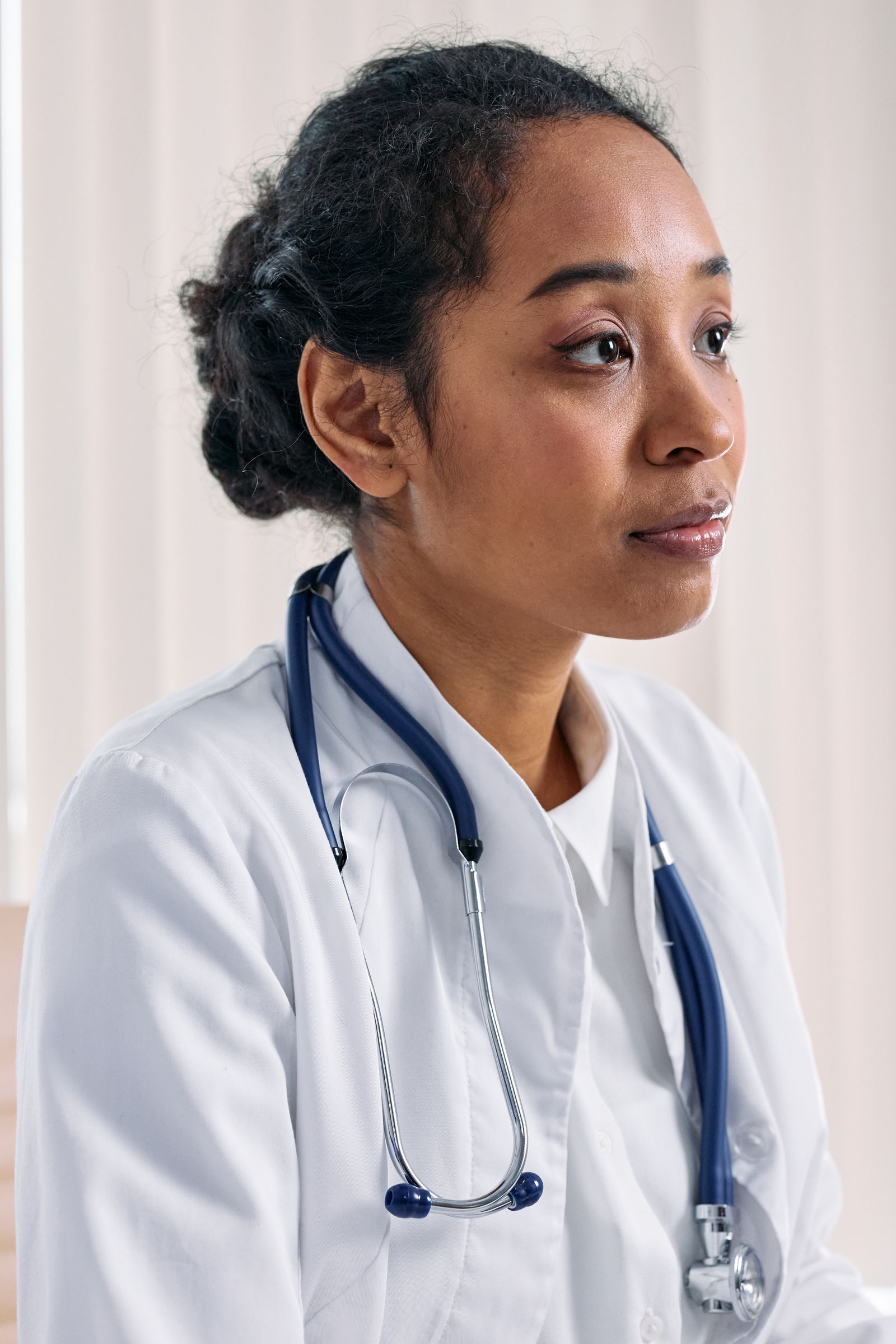 A Black woman physician in a white coat and stethoscope, the kind of gastroenterologist or hepatologist who manages chronic liver disease and orders liver cancer surveillance.